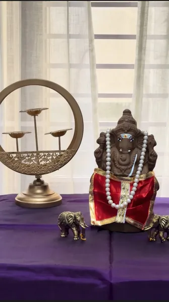 Clay Ganesha idol decorated with red silk and pearls on a Ganesh Chaturthi home mandap