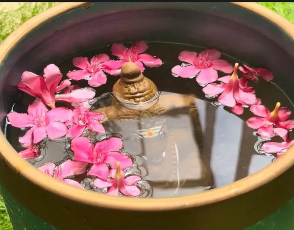Clay Ganesha idol dissolving in a pot of water with flowers during visarjan at home
