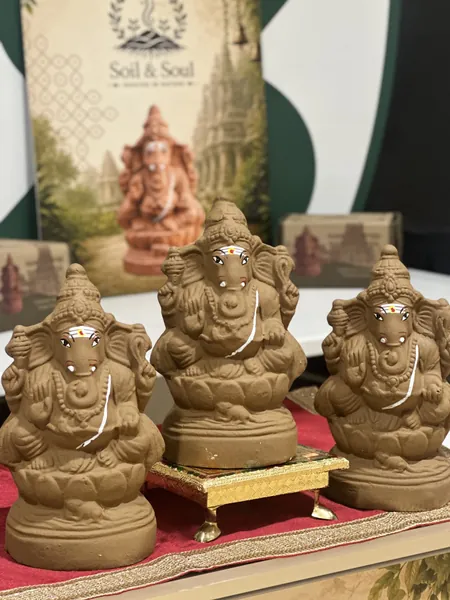 Three eco-friendly plantable clay Ganesha idols displayed on a decorated table